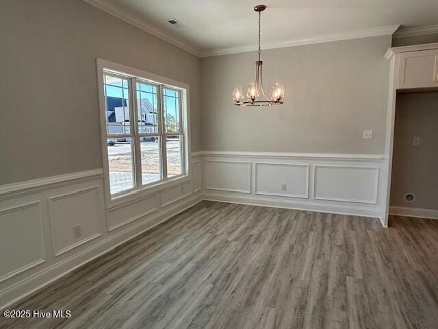 unfurnished dining area with crown molding, hardwood / wood-style floors, and a chandelier