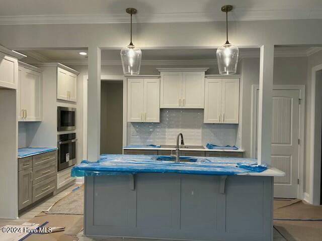 kitchen with white cabinets, decorative light fixtures, and tasteful backsplash