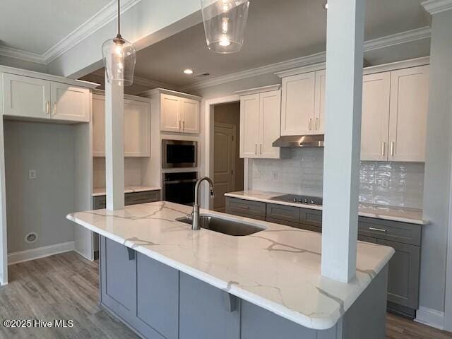 kitchen featuring an island with sink, sink, and white cabinets