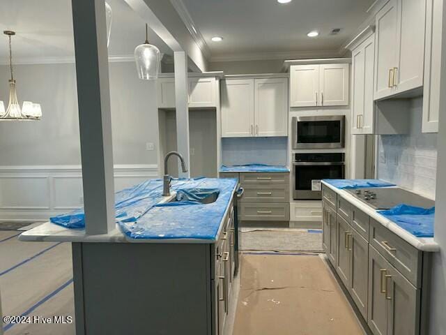 kitchen featuring stainless steel appliances, a kitchen island, crown molding, pendant lighting, and white cabinets