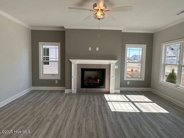 unfurnished living room with a tiled fireplace, ornamental molding, dark wood-type flooring, and ceiling fan