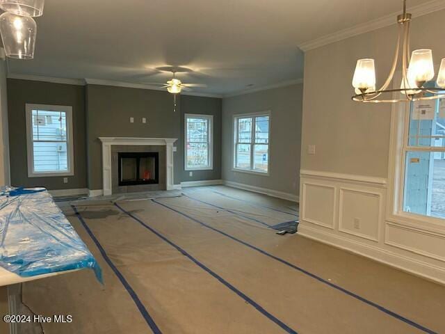 unfurnished living room with ceiling fan with notable chandelier and ornamental molding