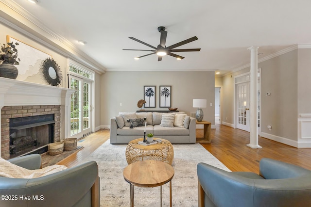 living room with decorative columns, hardwood / wood-style floors, ornamental molding, and a fireplace