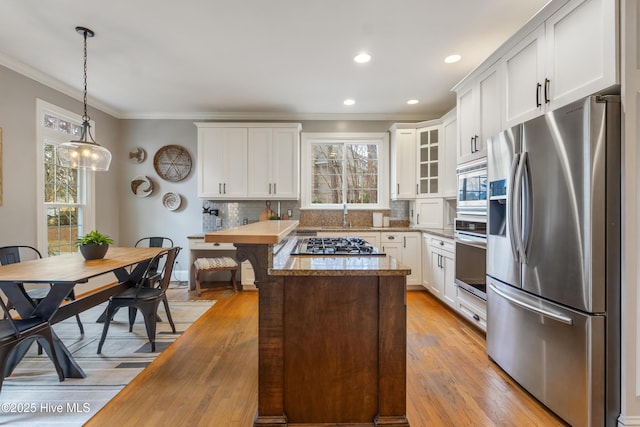 kitchen featuring butcher block counters, appliances with stainless steel finishes, white cabinetry, decorative backsplash, and pendant lighting