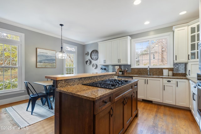 kitchen featuring a center island, light hardwood / wood-style floors, tasteful backsplash, decorative light fixtures, and black gas cooktop