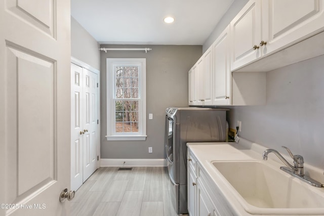 clothes washing area with sink, cabinets, and washing machine and clothes dryer