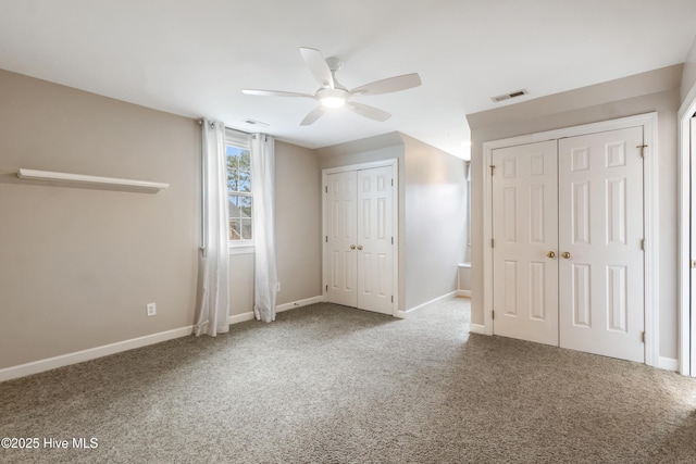 unfurnished bedroom featuring ceiling fan, carpet, and multiple closets