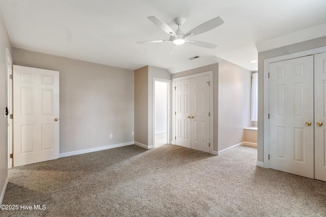 unfurnished bedroom with carpet floors, two closets, and ceiling fan