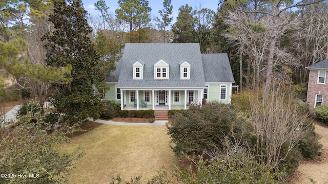 new england style home featuring covered porch and a front lawn