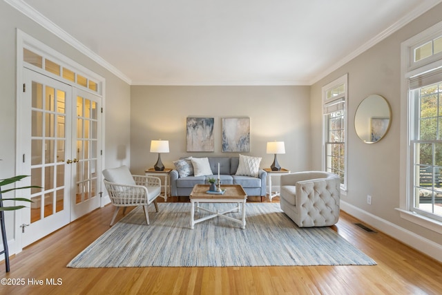 living room with light hardwood / wood-style floors, crown molding, and french doors