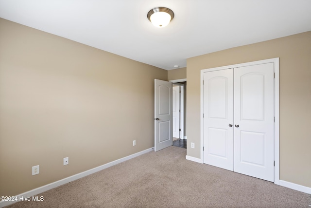 unfurnished bedroom with light colored carpet and a closet