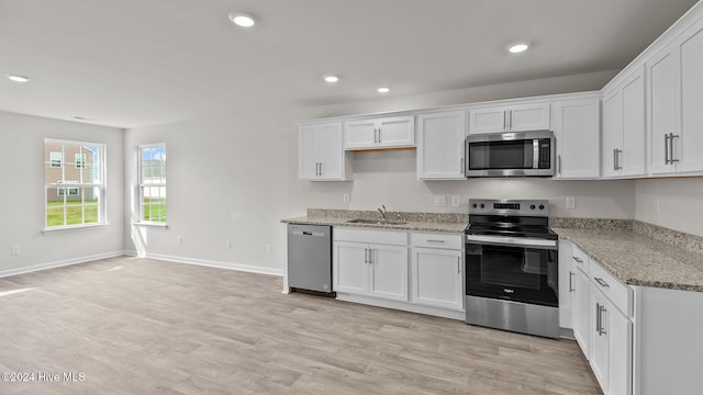 kitchen featuring white cabinets, stainless steel appliances, light wood-style floors, a sink, and recessed lighting