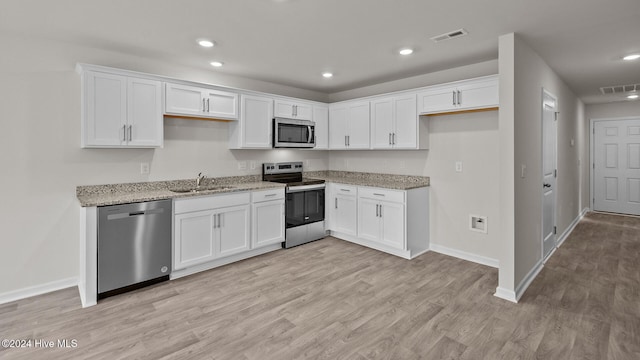 kitchen featuring appliances with stainless steel finishes, a sink, visible vents, and white cabinets