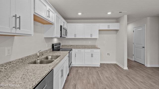 kitchen featuring white cabinets, light wood-style flooring, stainless steel appliances, and a sink