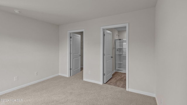 unfurnished bedroom with a spacious closet, carpet flooring, and baseboards