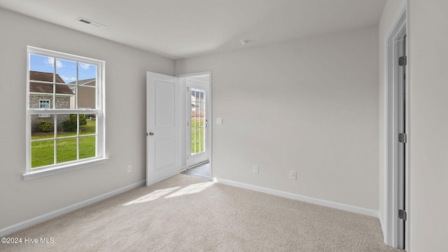 interior space with carpet floors, baseboards, multiple windows, and visible vents