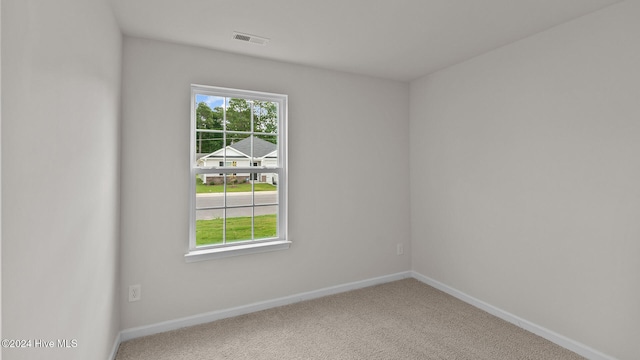 unfurnished room with carpet floors, visible vents, baseboards, and a wealth of natural light