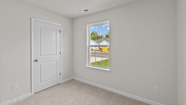 carpeted spare room with visible vents and baseboards