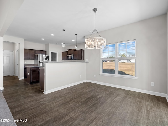 kitchen with stainless steel appliances, dark brown cabinetry, dark hardwood / wood-style flooring, and hanging light fixtures