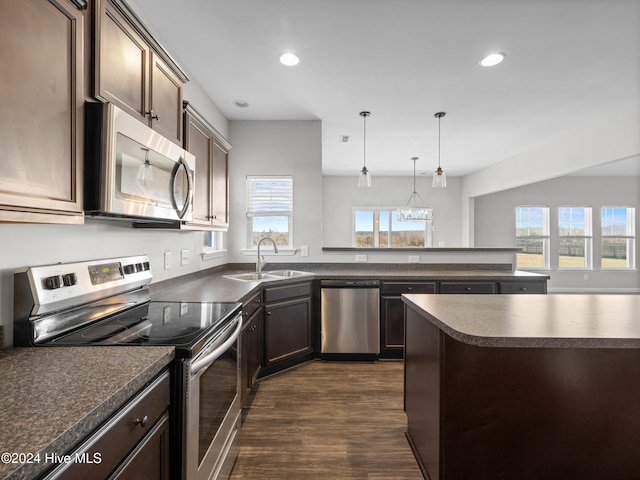 kitchen with dark brown cabinetry, sink, stainless steel appliances, dark hardwood / wood-style flooring, and decorative light fixtures