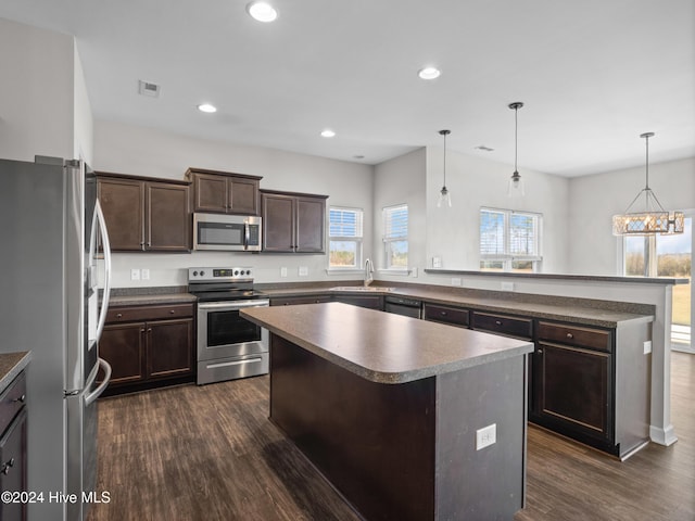 kitchen with pendant lighting, a notable chandelier, a kitchen island, dark hardwood / wood-style flooring, and stainless steel appliances