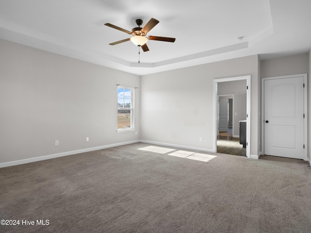 unfurnished room featuring ceiling fan, carpet floors, and a tray ceiling