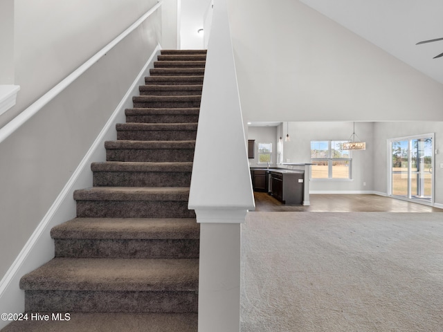 stairs featuring an inviting chandelier and high vaulted ceiling