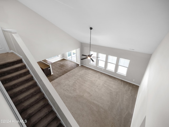 stairway with ceiling fan, carpet floors, and lofted ceiling