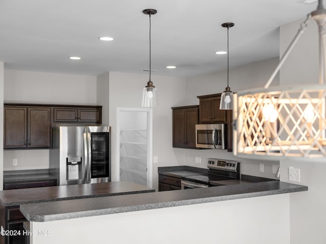 kitchen featuring kitchen peninsula, decorative light fixtures, stainless steel appliances, and dark brown cabinets