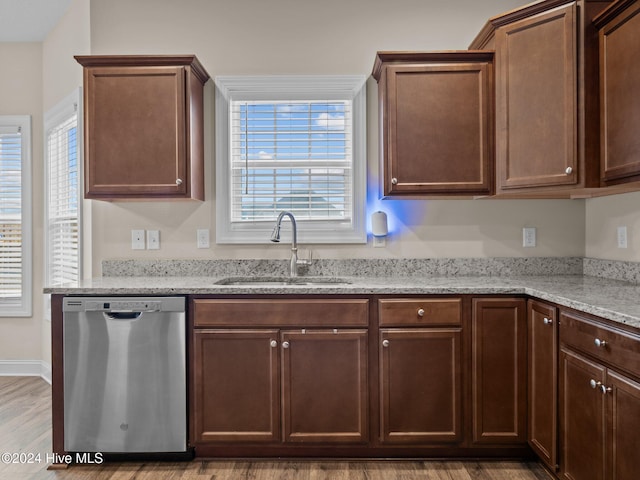 kitchen featuring light stone countertops, hardwood / wood-style floors, stainless steel dishwasher, and sink