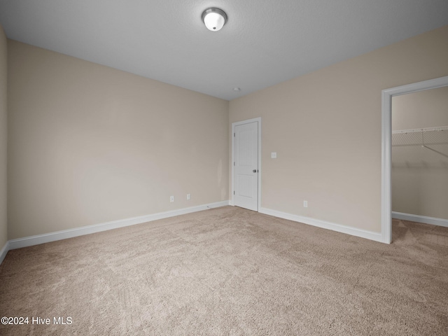 unfurnished bedroom with a spacious closet, carpet floors, and a closet