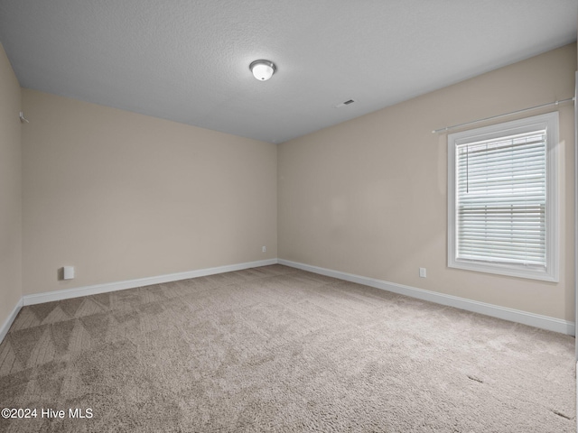 unfurnished room with carpet flooring and a textured ceiling