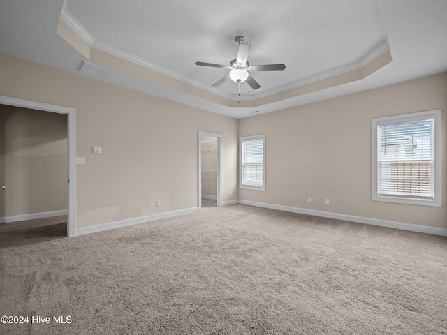 unfurnished bedroom with a tray ceiling, ceiling fan, crown molding, and carpet floors