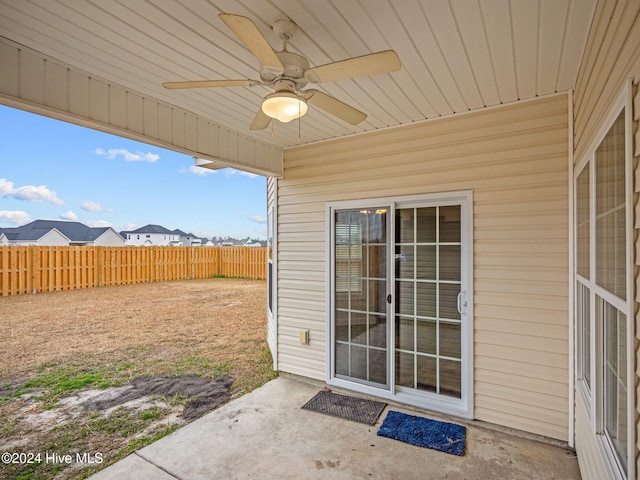 view of exterior entry with ceiling fan and a patio area