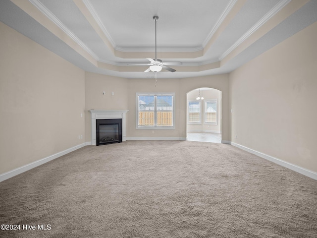 unfurnished living room with carpet flooring, a tray ceiling, ceiling fan, and crown molding