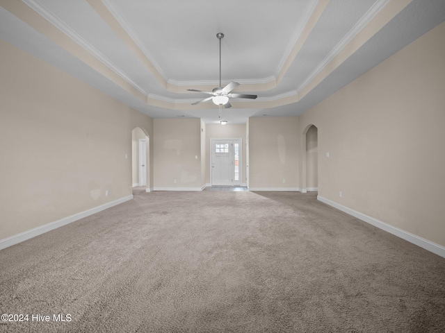 empty room with carpet, a tray ceiling, ceiling fan, and ornamental molding