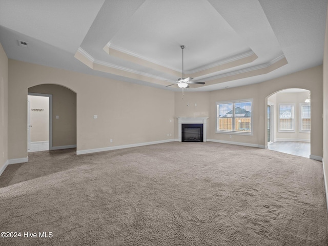 unfurnished living room featuring light carpet, a raised ceiling, ceiling fan, and ornamental molding