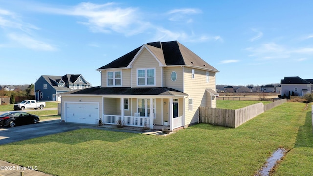 traditional-style home with an attached garage, covered porch, fence, driveway, and a front lawn