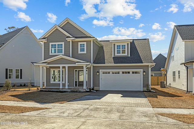 view of front of home featuring a garage, central air condition unit, and a porch