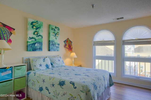 bedroom featuring a textured ceiling and light hardwood / wood-style flooring