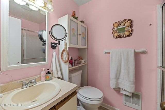 bathroom with vanity, toilet, a shower with door, and heating unit