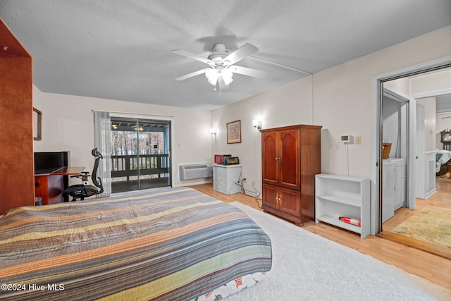 bedroom with a textured ceiling, light hardwood / wood-style floors, a wall unit AC, and ceiling fan