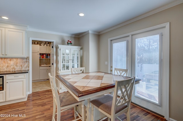 dining area with light hardwood / wood-style floors, a wealth of natural light, and crown molding