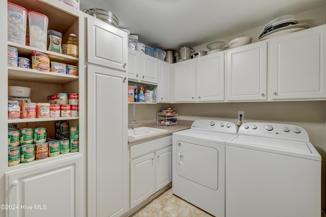 laundry room with cabinets, washing machine and dryer, and sink