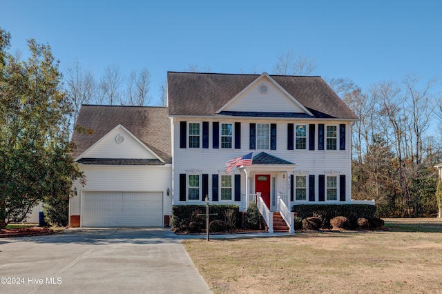 colonial home with a garage and a front lawn