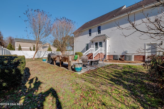 rear view of property featuring a yard, cooling unit, and a patio area