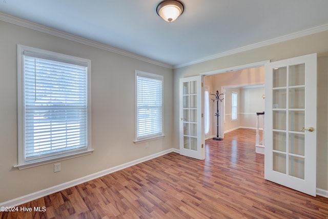 empty room with wood-type flooring, crown molding, a wealth of natural light, and french doors