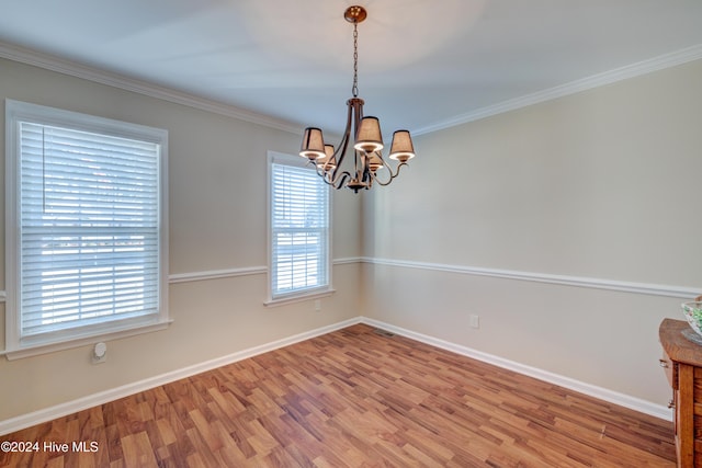 spare room featuring hardwood / wood-style floors, crown molding, and an inviting chandelier