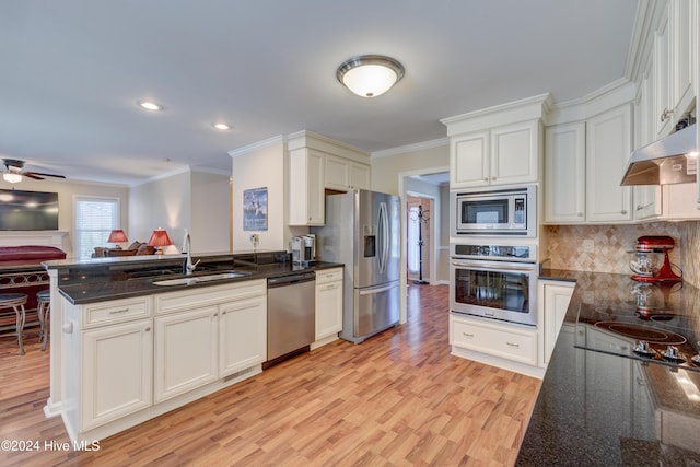 kitchen with kitchen peninsula, appliances with stainless steel finishes, backsplash, sink, and dark stone countertops