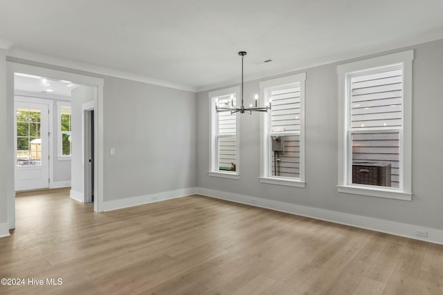 unfurnished dining area with a notable chandelier, crown molding, and light wood-type flooring